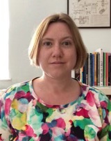 Rosie, a white woman in her late 30s. She has blonde hair and is wearing a colourful top.